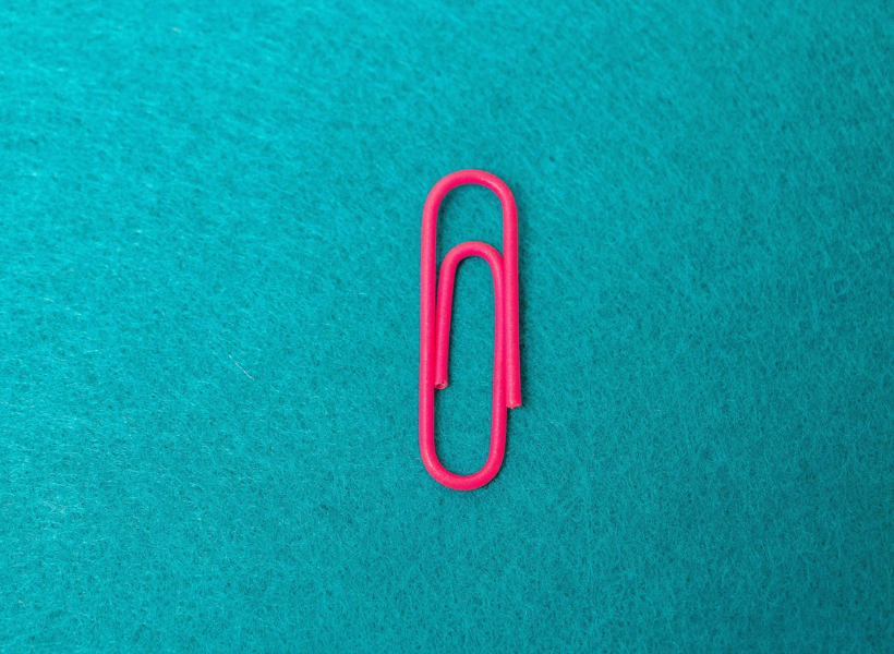 A pink paper clip on a blue background