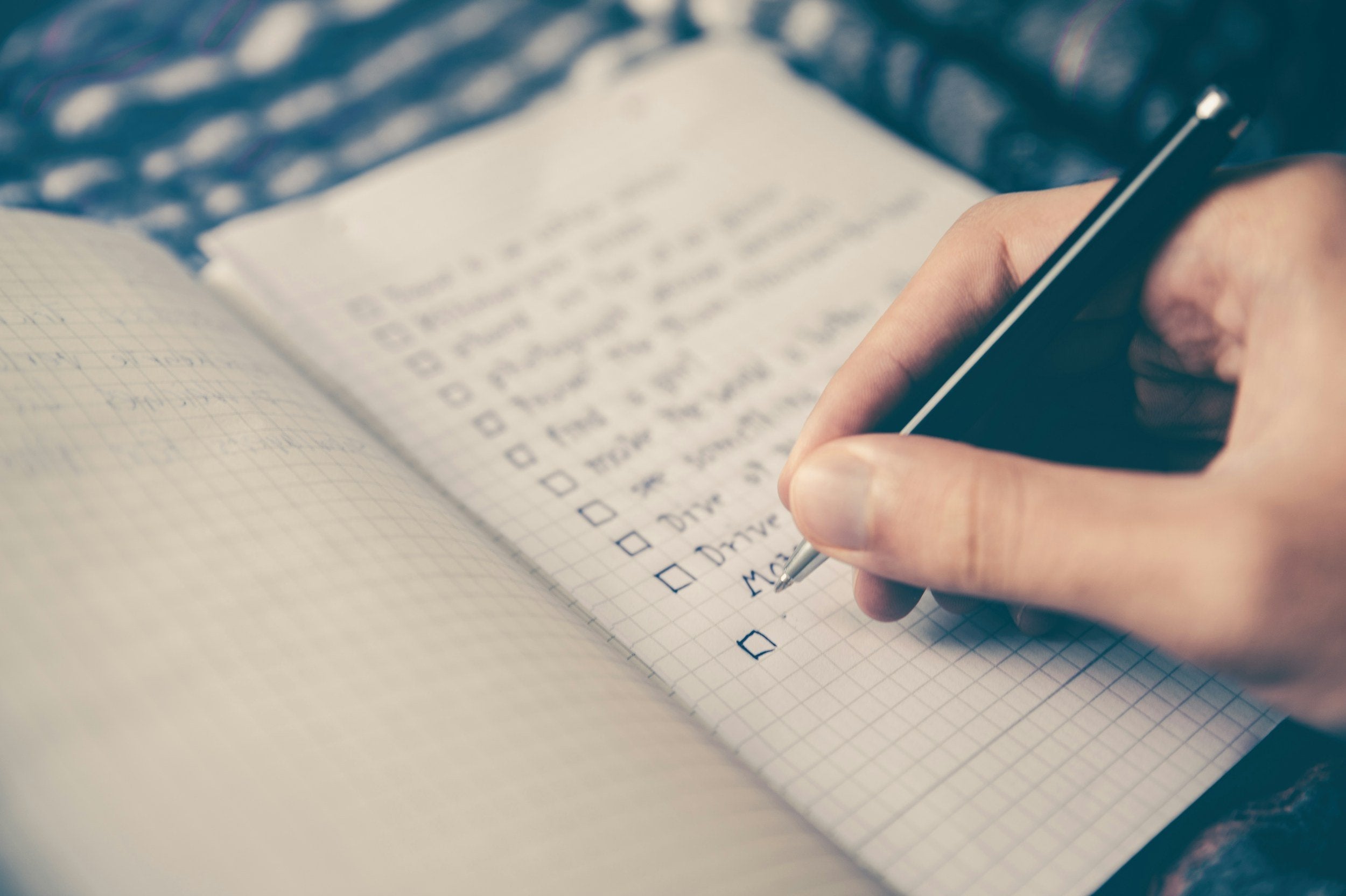 Someone writing a checklist in their notebook