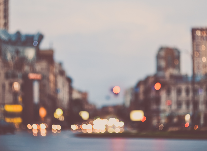 A blurry image of a city skyline and headlights in the distance 