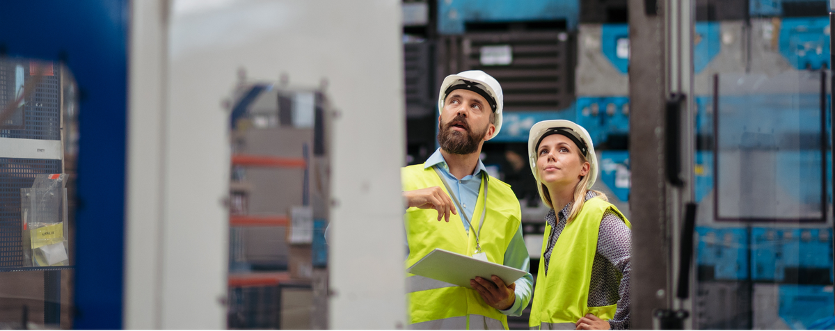 Two workers talk in a manufacturing warehouse.